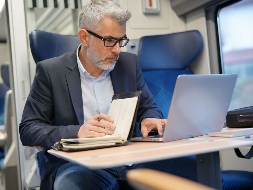 Mann arbeitet im Zug mit Laptop